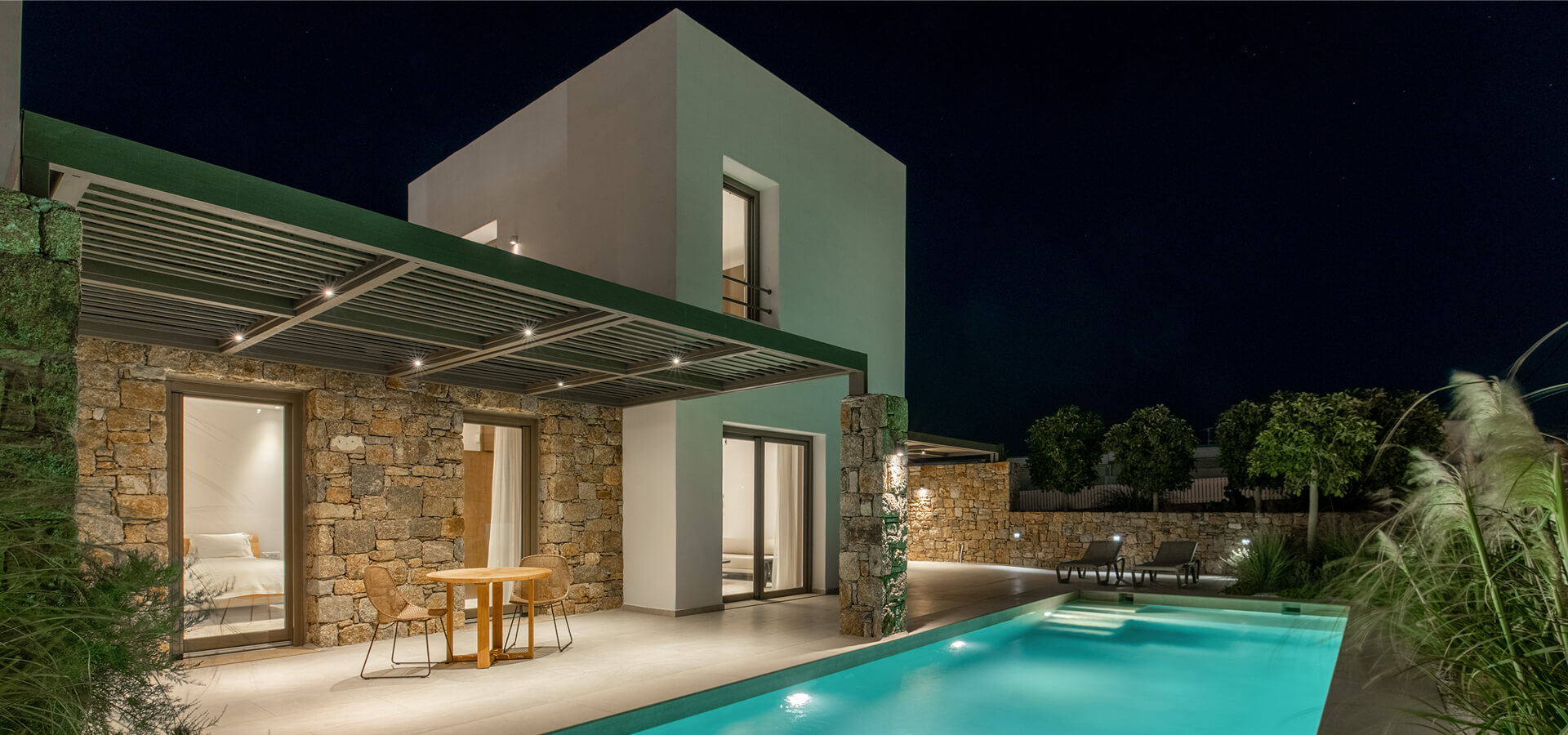Night view of a modern suite with illuminated pool and patio