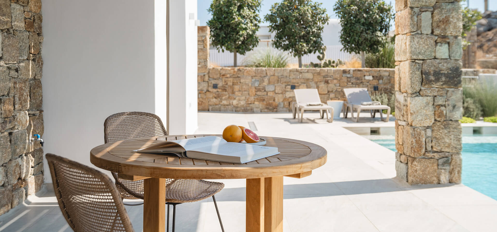A book and fruits on a table by the pool
